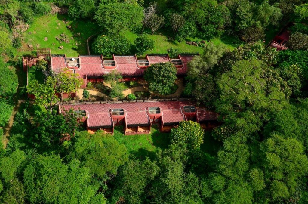 Die beiden Flügel der Amboseli Serena Safari Lodge mit roten Dächern aus der Luft, zwischen Bäumen