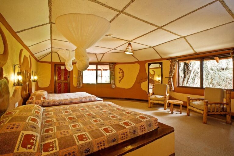 Ein Zimmer mit zwei Betten, Tagesdecken mit Elefantenmuster und an der Decke geknoteten Moskitonetzen