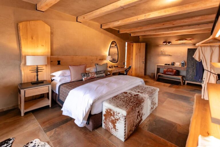 Eine Suite mit großem Bett, einer Bank mit Kuhfell, einer Kaffeeecke und einem aufgehängten Bademantel