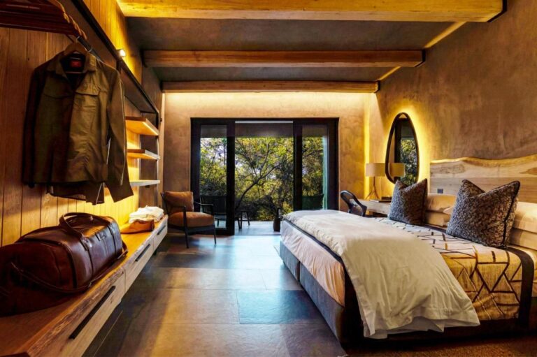 Eine Suite mit großem Bett, offen zu einer Terrasse zwischen den Bäumen