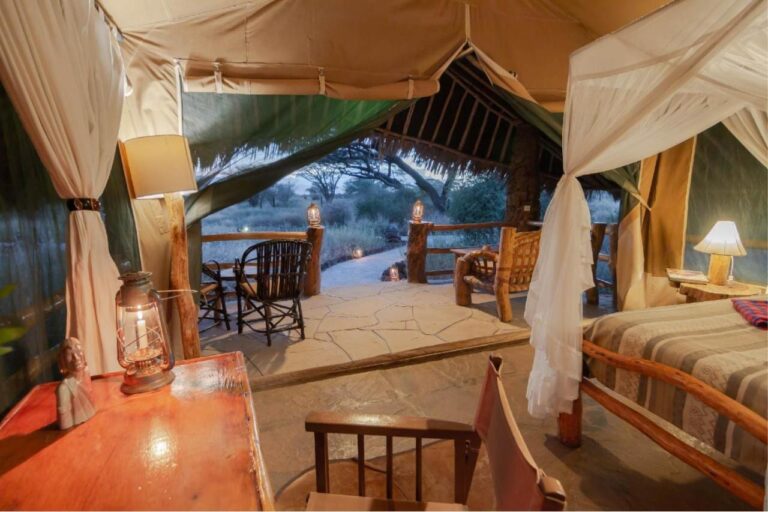 Der Schreibtisch eines Zeltes mit einer Laterne, gegenüber der strohgedeckten Terrasse und dem Busch
