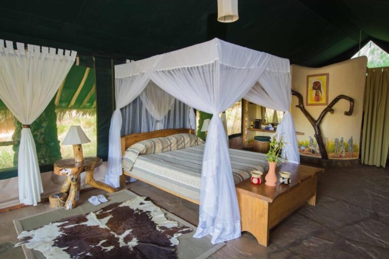 Ein Zelt mit dunkelgrünen Wänden, einem Bett unter einem Moskitonetz, einer Truhe und einem Kuhfell auf dem Boden