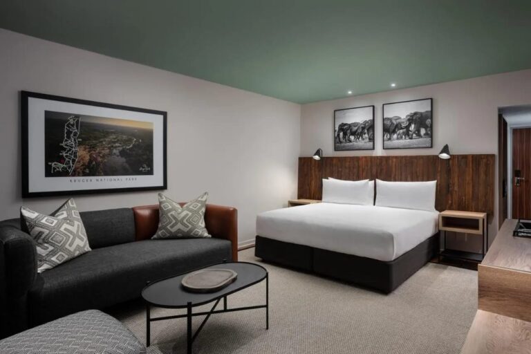 Ein Deluxe-Zimmer mit großem Bett und Sofa im Kruger Gate Hotel