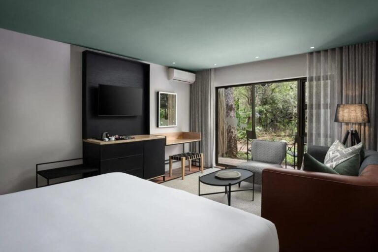 Ein Deluxe-Zimmer, durch eine Fensterfront zu den Bäumen geöffnet