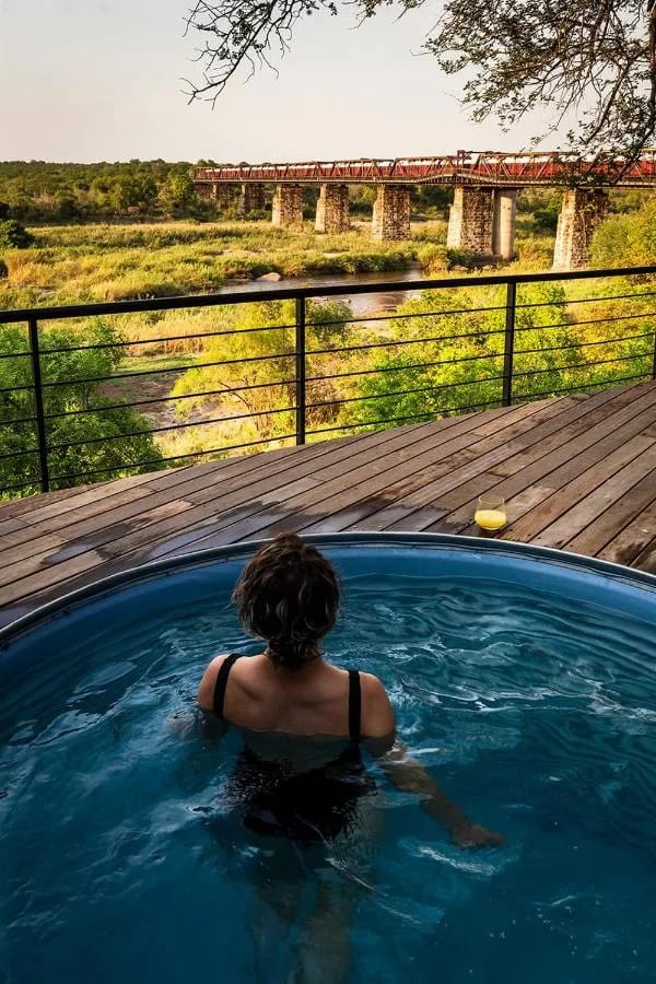 Eine Frau im kleinen Pool einer Suite, mit Blick auf den Zug auf der Brücke