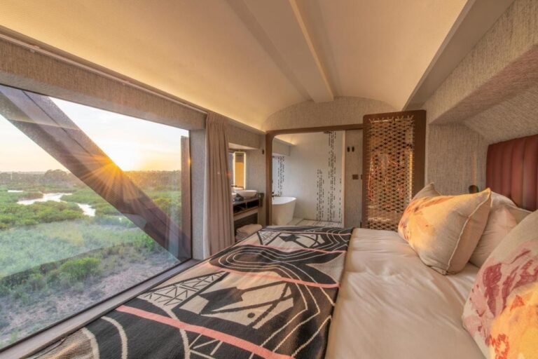 Das Innere eines Waggons des Kruger Shalati, das Bett vor einem großen Fenster zum Fluss, die Badewanne im Hintergrund