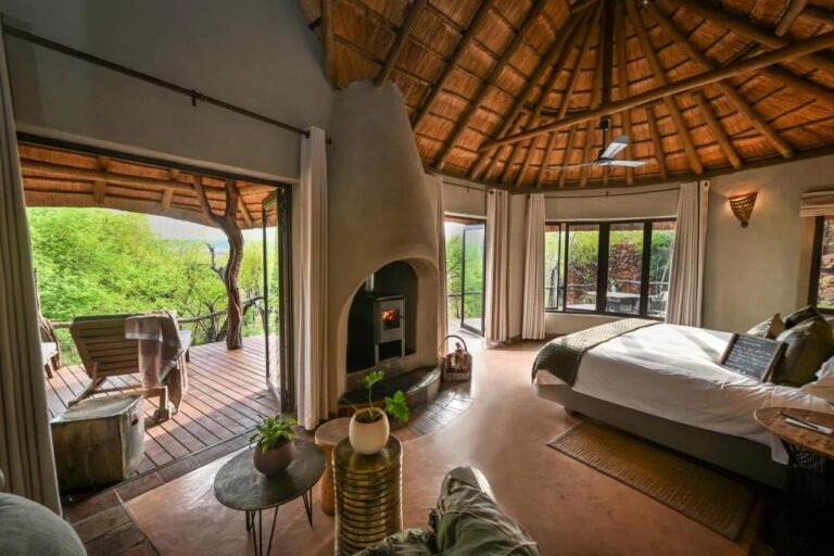 Eine Suite, offen zu einer Terrasse mit Blick auf die Bäume, mit Holzofen und großem Bett