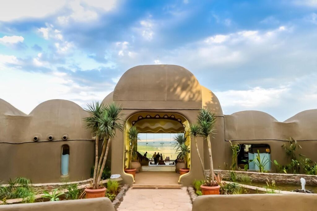 Der Eingang der Mara Serena Safari Lodge mit kuppelförmigen Lehmmauern, offen zur Savanne der Masai Mara