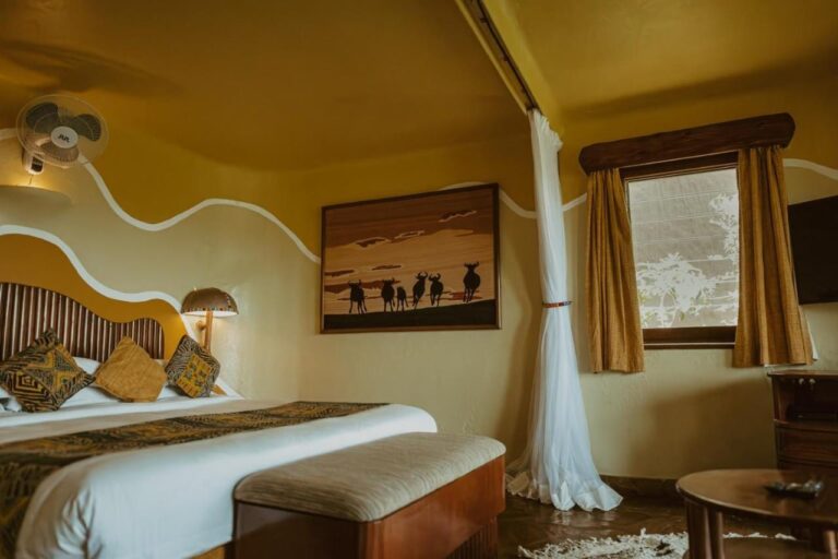 Ein Zimmer mit einem Bild von Gnu-Silhouetten über dem Bett und einem Wandventilator