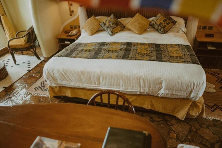 Ein großes Bett vom Schreibtisch aus, auf einem Boden mit Steinplatten