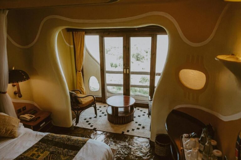 Ein Zimmer mit runden Wänden in der Mara Serena Safari Lodge, mit Sitzecke vor der Balkontür