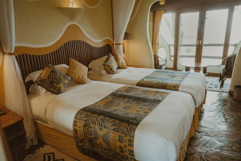 Ein Zimmer mit zwei Betten, durch eine Fenstertür zum Balkon geöffnet