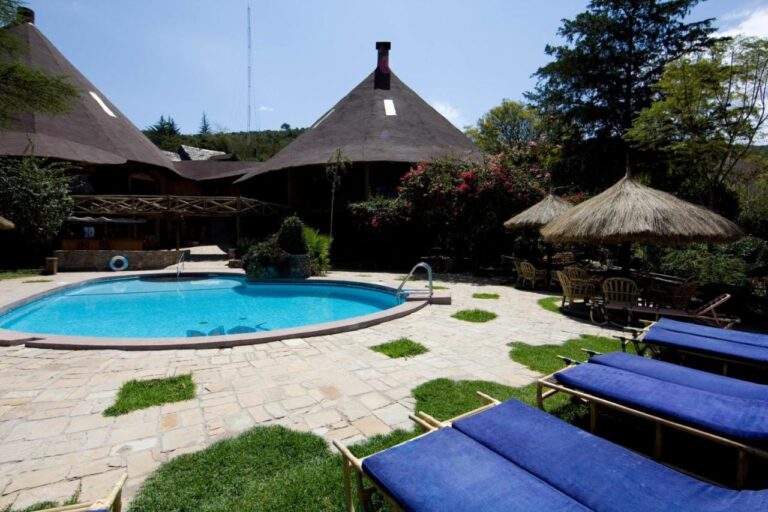 Liegestühle mit blauen Kissen am Pool, neben Strohschirmen