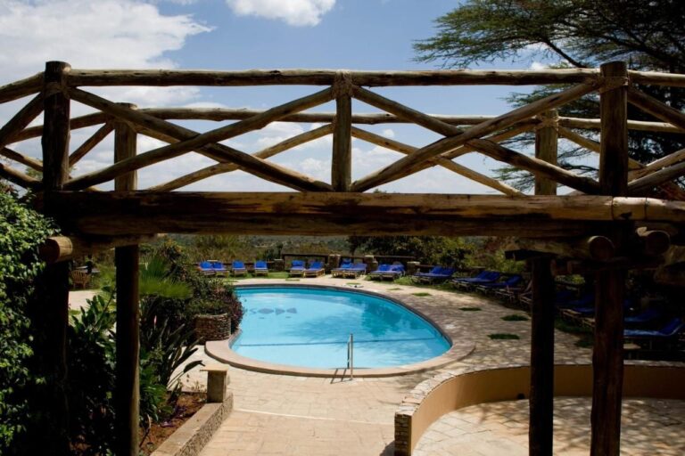 Der Pool, gesehen durch eine Pergola aus Rundhölzern, umgeben von Liegestühlen