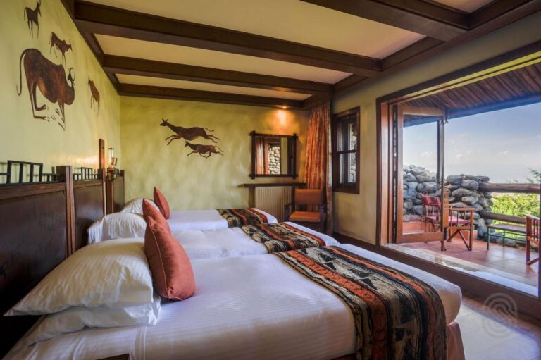 Ein Zimmer mit drei Betten, offen zu einem Balkon mit Steinmauern