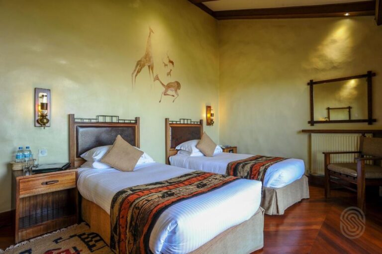 Ein Zweibettzimmer mit einer Giraffe und Antilopen, an die Wand gemalt
