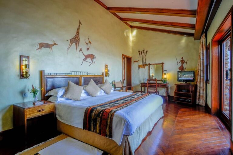 Ein Zimmer mit großem Bett, Schreibtisch, Fernseher und einer an die Wand gemalten Giraffe