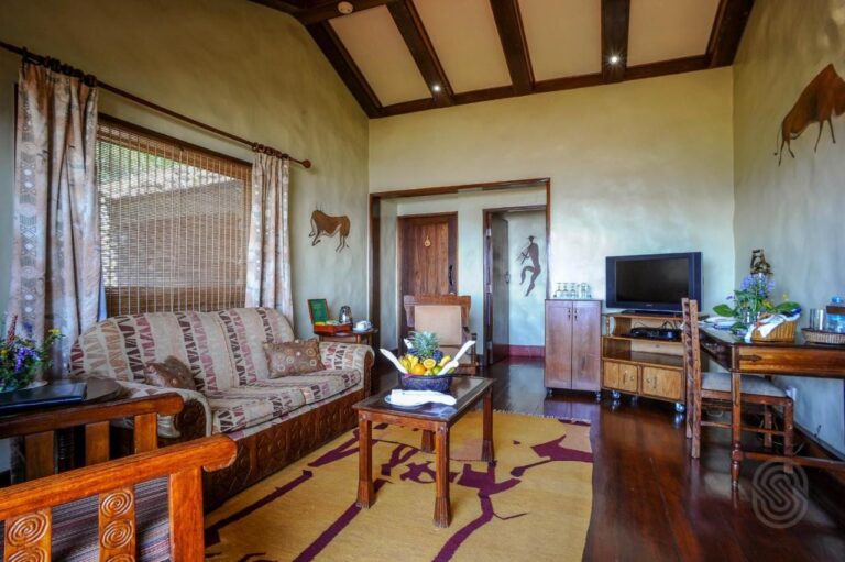 Das Wohnzimmer einer Suite mit gemustertem Sofa, Obstkorb und Fernseher