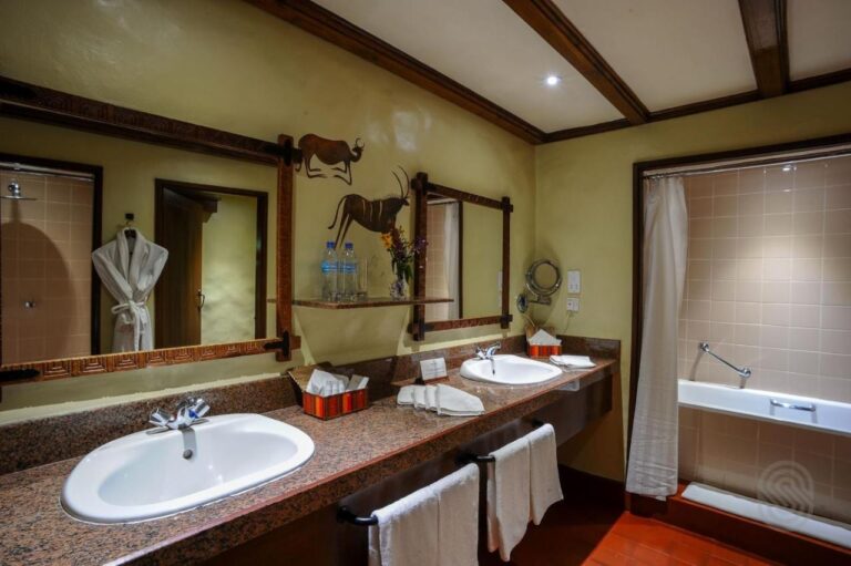 Ein Bad mit zwei Waschbecken, einer Badewanne und einem aufgehängten Bademantel
