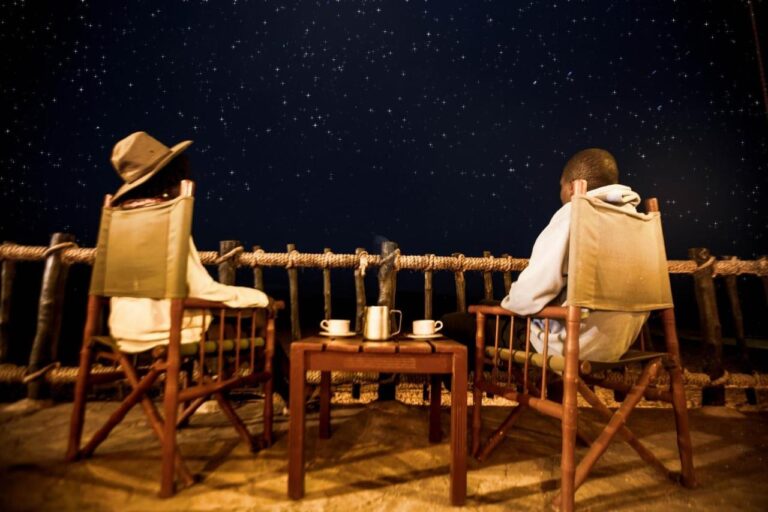 Zwei Personen sitzen in Stoffsesseln auf der Terrasse, zwei Tassen auf dem Tisch, unter einem Sternenhimmel