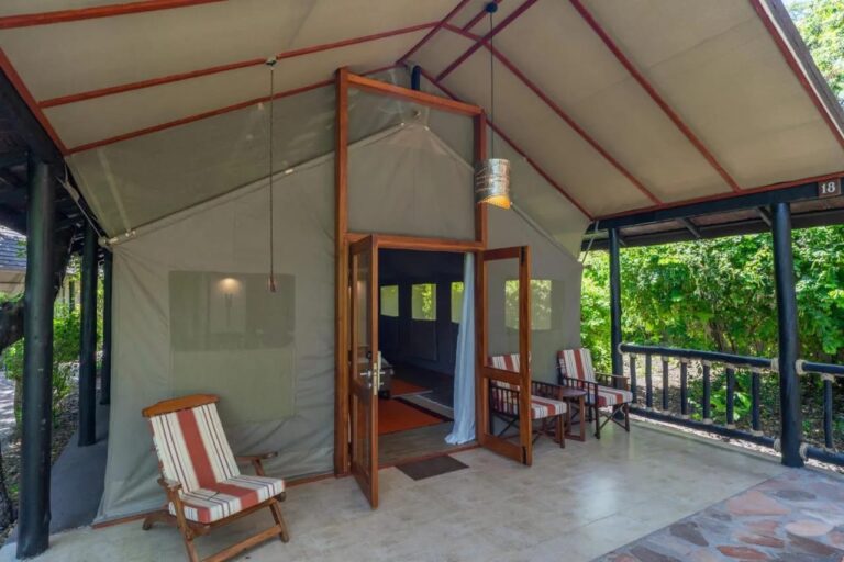 Der Eingang eines Zelts unter einem Dach, mit gestreiften Stühlen auf der Veranda