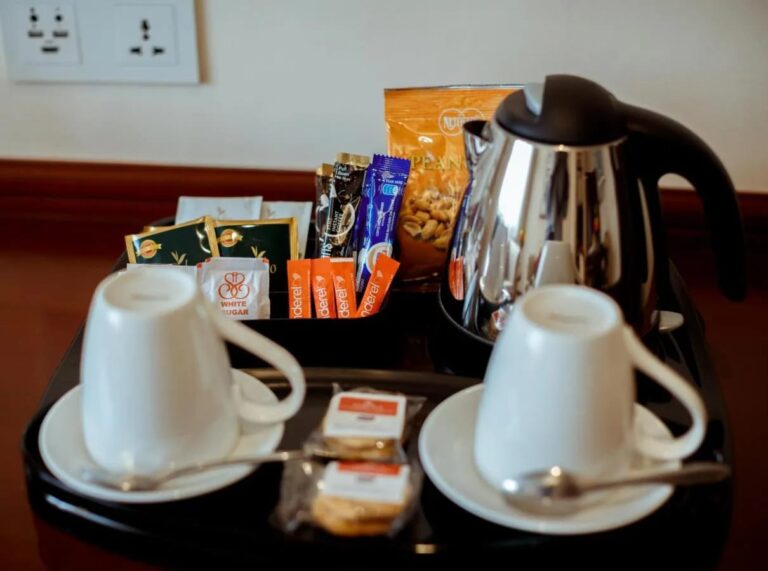 Ein Tablett mit Wasserkocher, zwei Tassen, Tee, Kaffee in Beuteln und Keksen