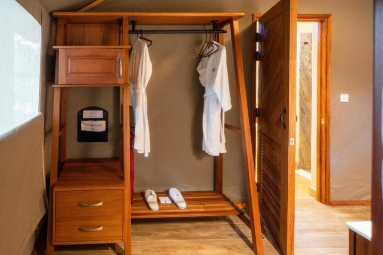 Ein offener Kleiderschrank mit zwei Bademänteln und Hausschuhen, neben der Badezimmertür
