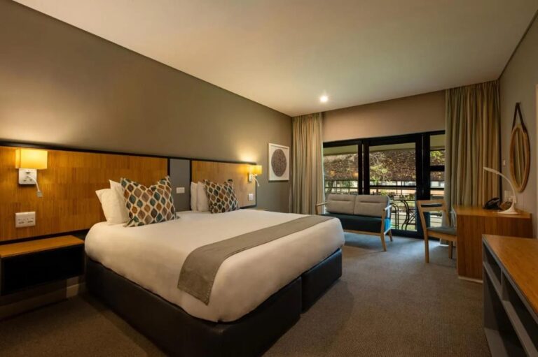 Ein Zimmer mit großem Bett, Sofa und Schreibtisch, offen zu einer Terrasse