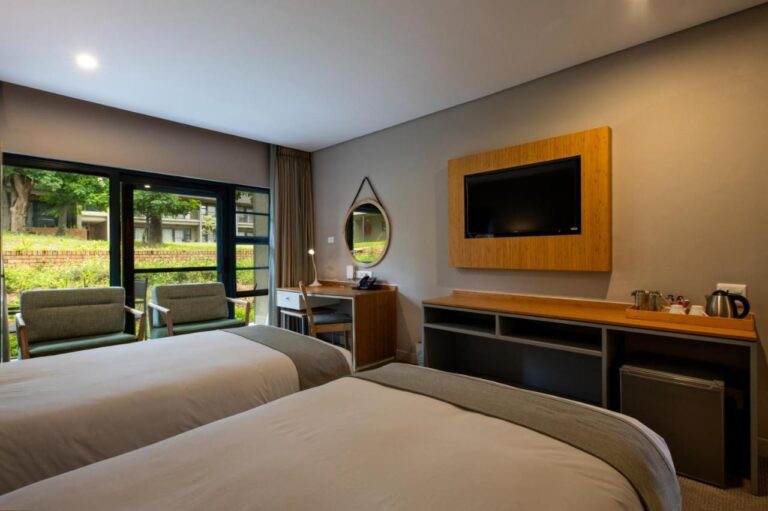 Ein Zimmer mit zwei Betten, Fernseher, Wasserkocher und Blick auf den Garten