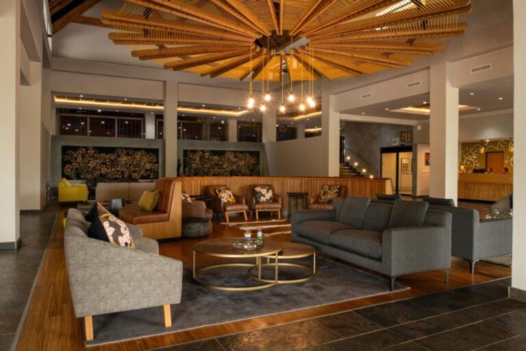 Die Lounge in der Lobby, mit grauen Sofas und Ledersesseln, unter einer Decke aus Holzlatten