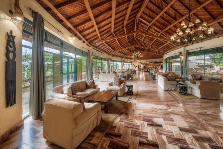 Die große Lounge der Lodge mit Sesseln und Fensterfronten unter einem Holzdachstuhl